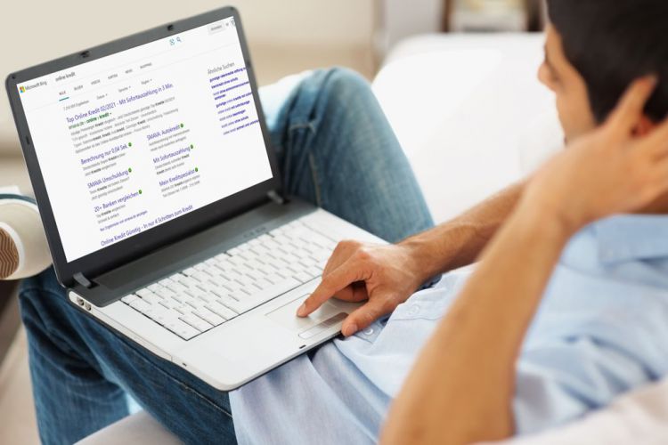 Ein Mann mit einem Laptop sucht im Internet nach einem Kredit